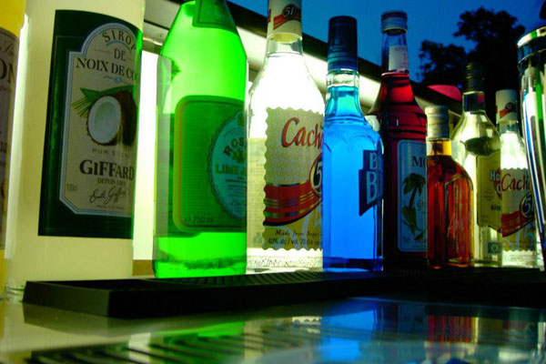 A line of bottles standing on top of a bar counter