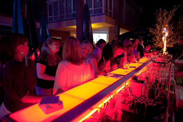 A group of ladies stands at a Justincase bar with orange lights on at a 28s Finest event in Germany